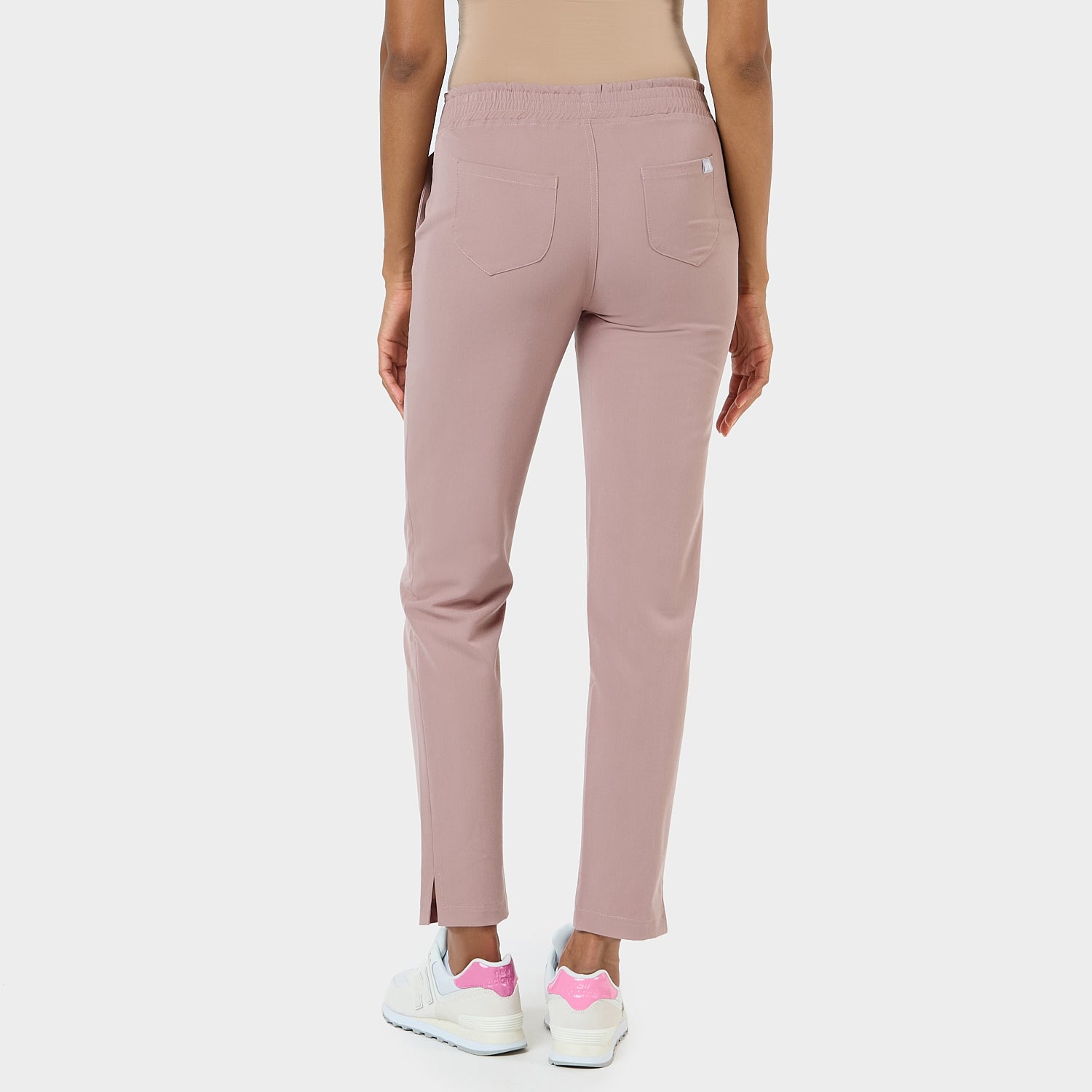 Damskie spodnie medyczne w kolorze dusty pink – widok z tyłu na kobiecie.