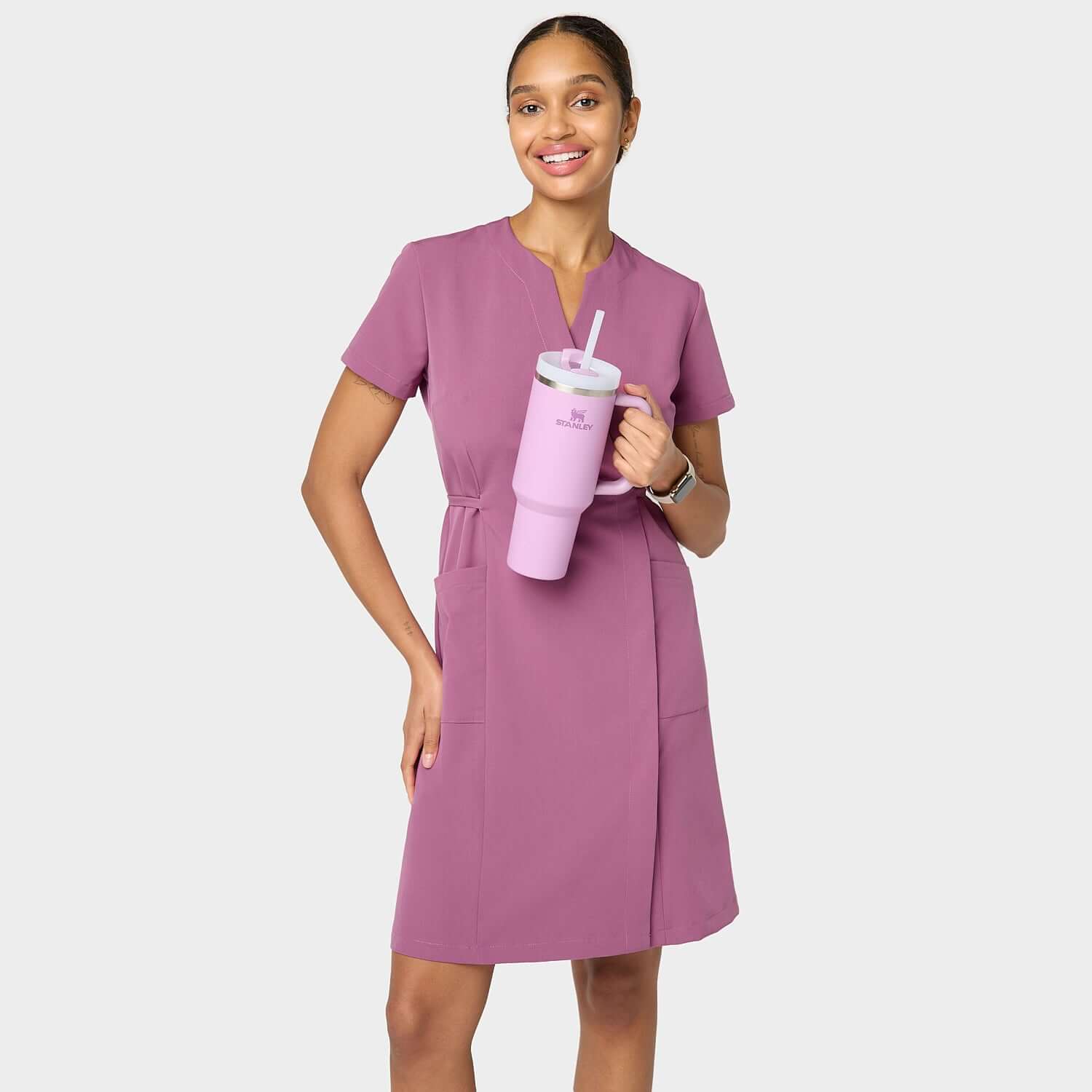 Modelka w sukience medycznej Kate w kolorze Berry Crush – nowoczesny, taliowany krój z krótkim rękawem i kieszeniami, idealna do pracy w placówkach medycznych.