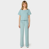 Bluza medyczna Gaja crop w kolorze CLOUDY BLUE od Vena Uniformy.
Modelka stoi na jasnym tle w pastelowym komplecie medycznym: bluza z krótkim rękawem oraz szerokie spodnie, zestawione z niebieskimi sneakersami.