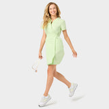 Modelka prezentująca sukienkę wiązaną medyczną KATE w kolorze Matcha. Ukazuje elegancję i nowoczesny styl w dynamicznym otoczeniu.
