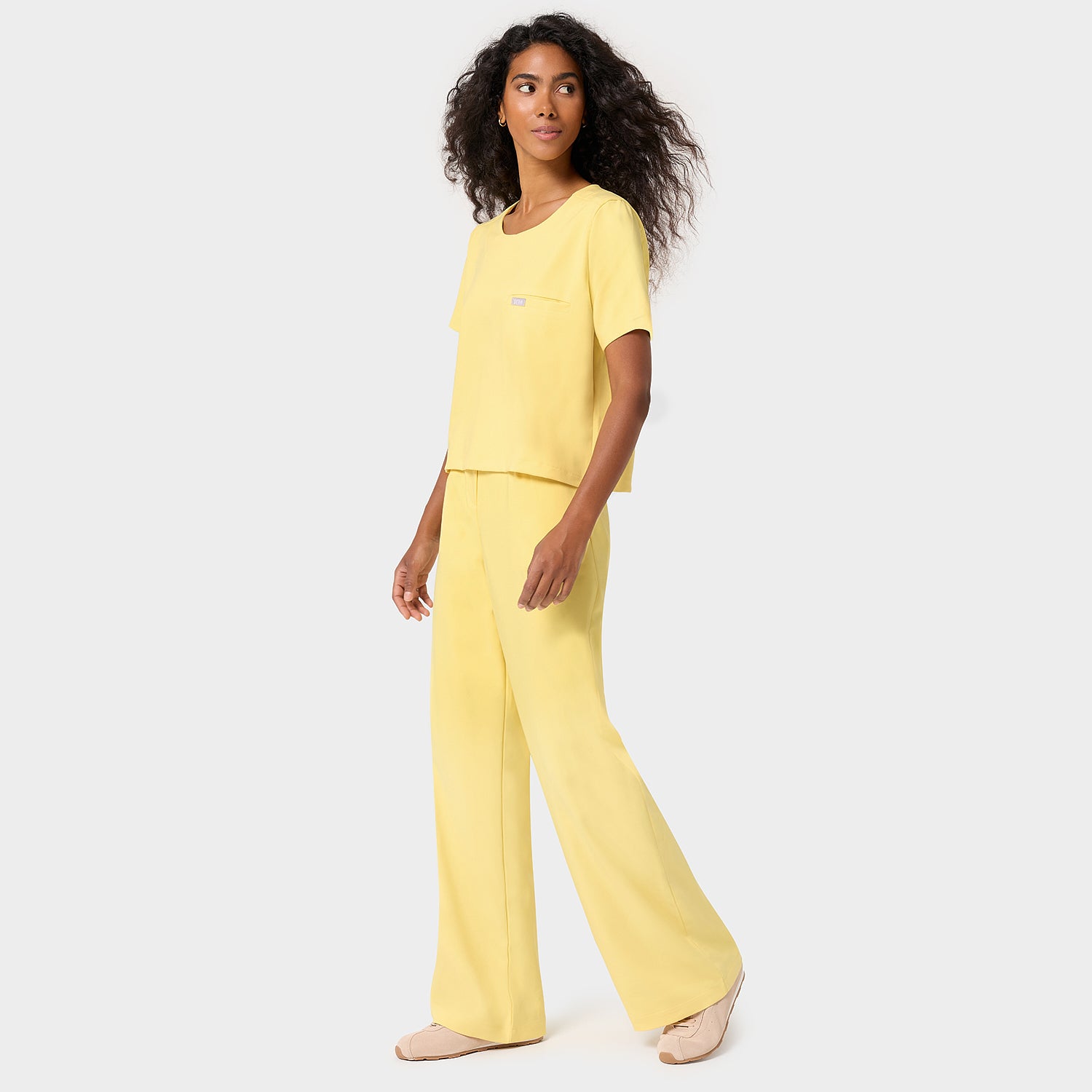Kobieta w szerokich spodniach medycznych Aura Butter Yellow — masłowo-żółte scrubs damskie z wysoką talią, kobieca odzież medyczna Vena Uniformy